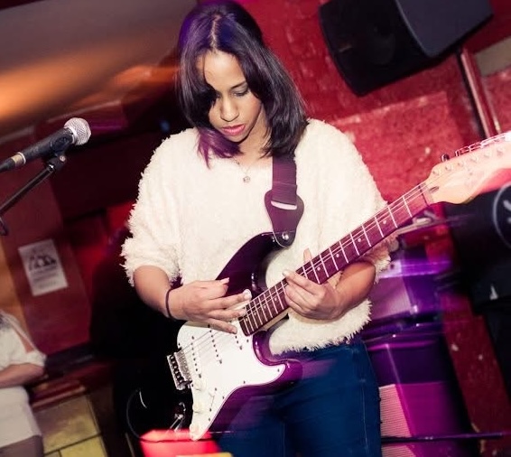 Zena playing electric guitar on stage